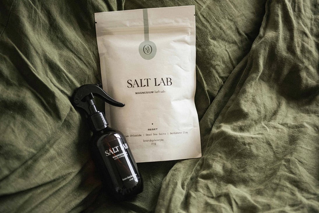 a spray bottle and bag of bath salts on a bed